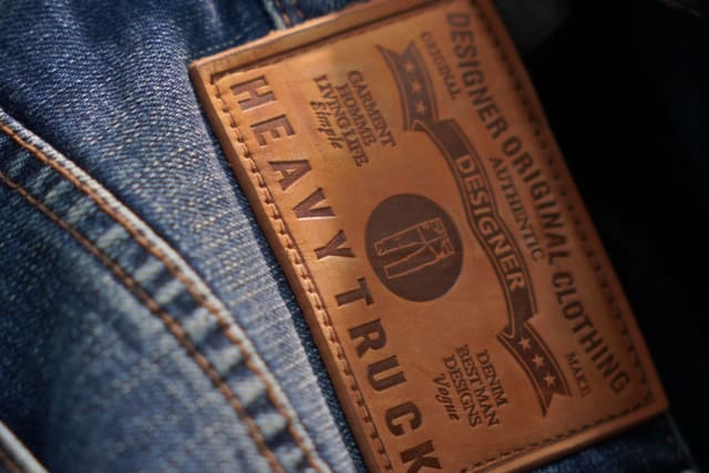 Close-up of a leather brand patch stitched onto the back waistband of a finished pair of jeans